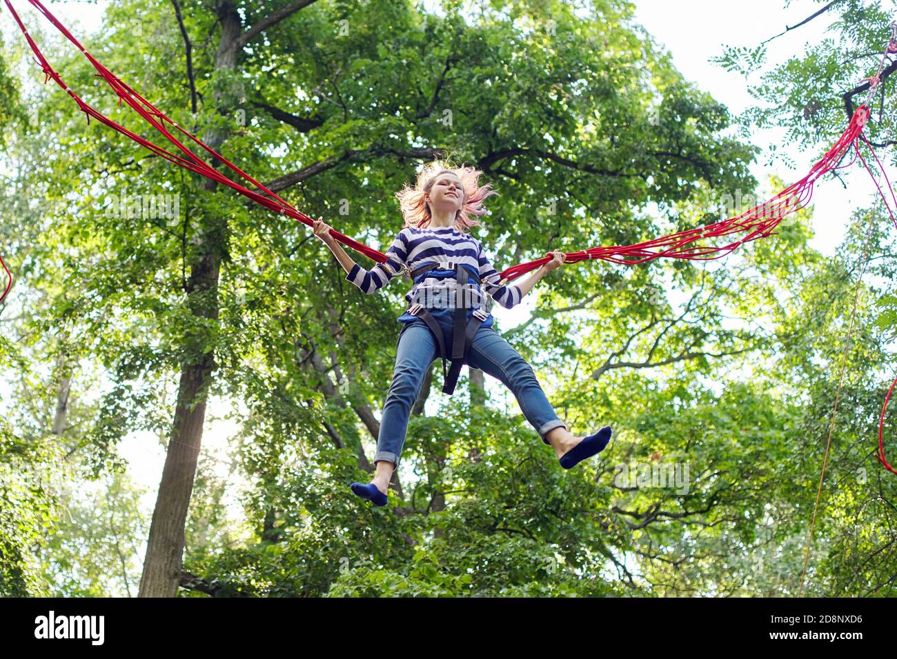 Teenager girl having fun jumping on trampoline with elastic ropes Stock