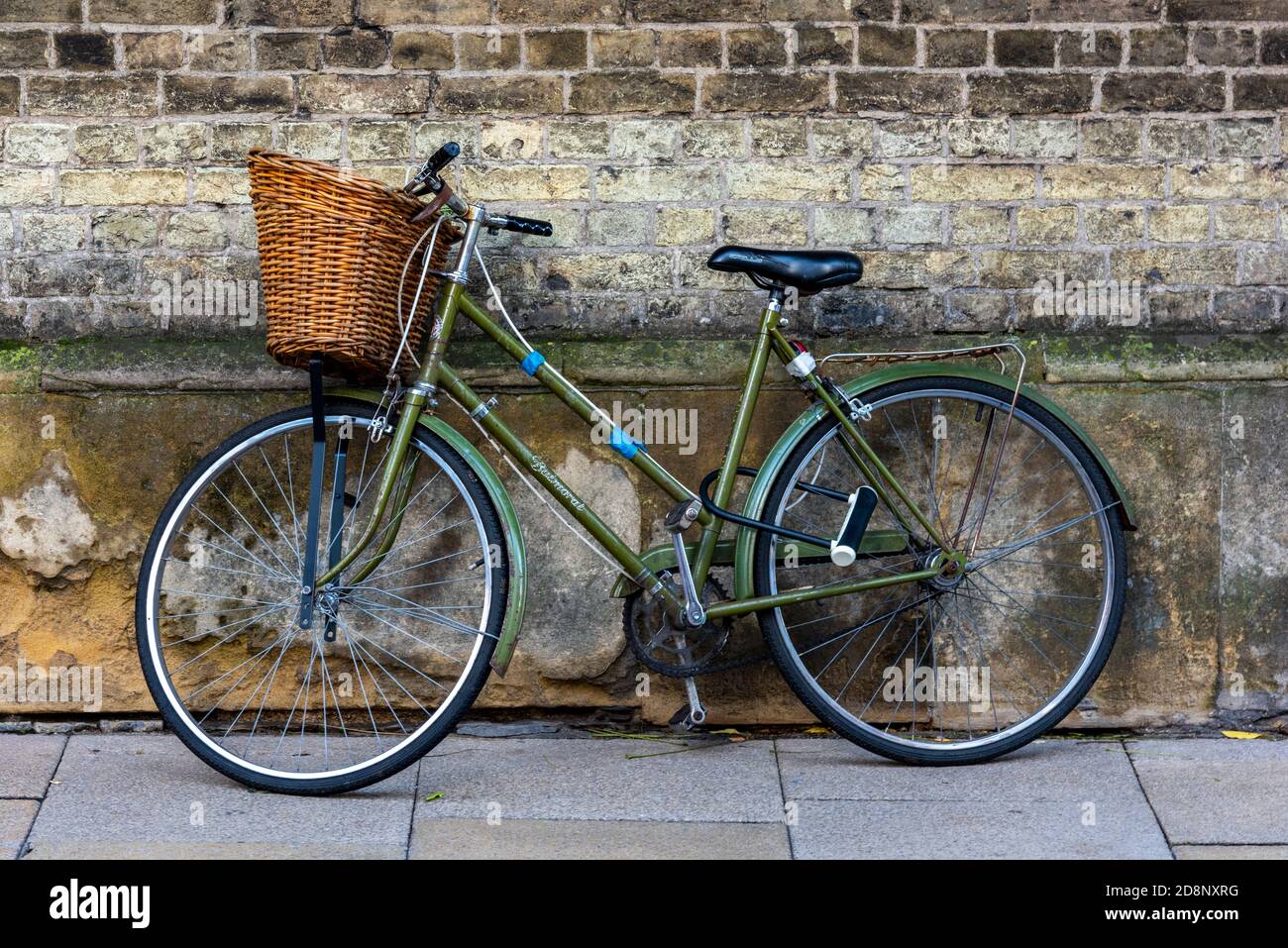old fashioned vintage ladies bicycle with a basket on the front for  shopping leaning against a wall in cambridge city centre Stock Photo - Alamy