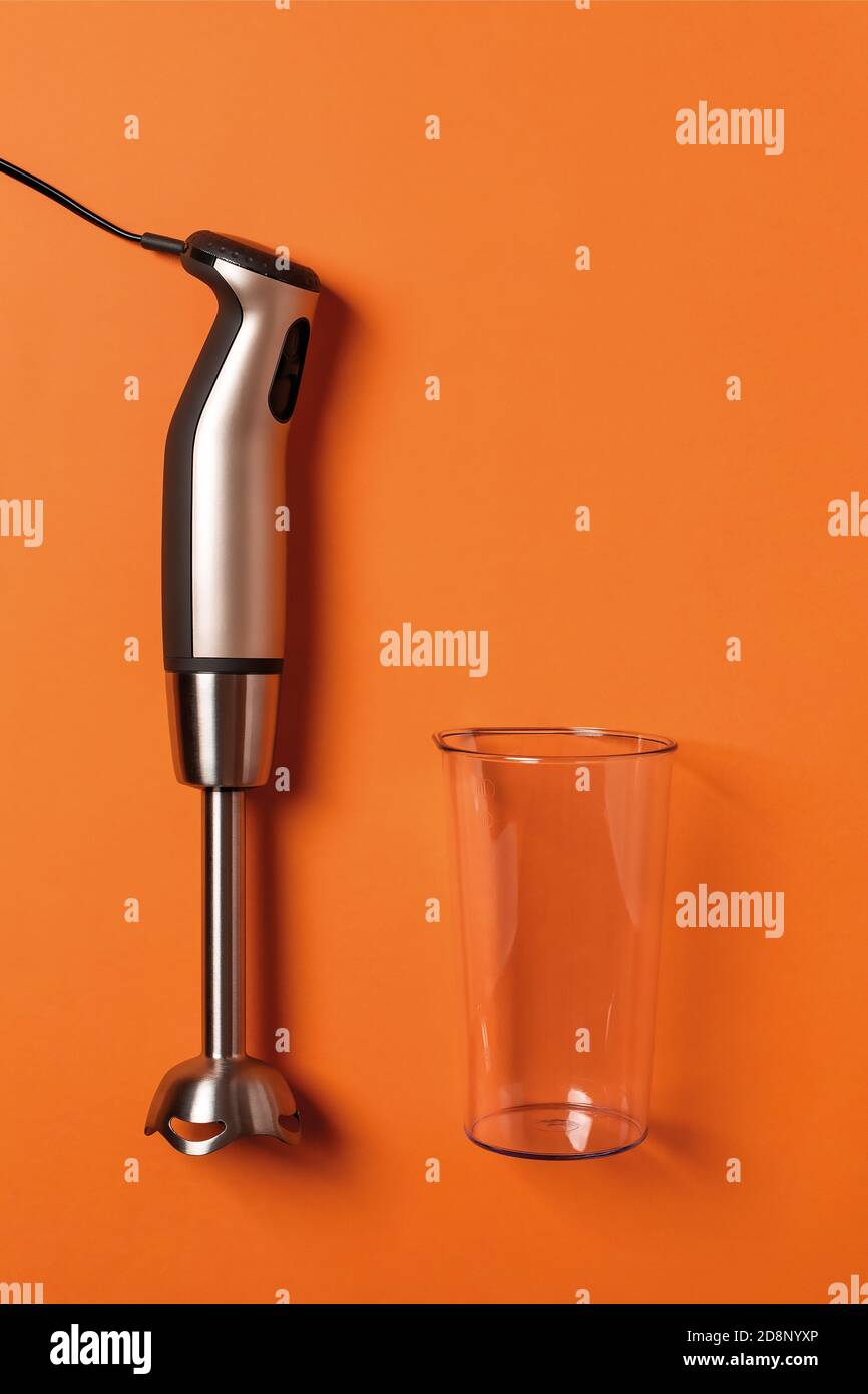 https://c8.alamy.com/comp/2D8NYXP/immersion-hand-blender-and-empty-cup-on-a-carrot-orange-background-modern-electric-kitchen-appliances-for-making-sauces-smoothies-puree-copy-space-2D8NYXP.jpg