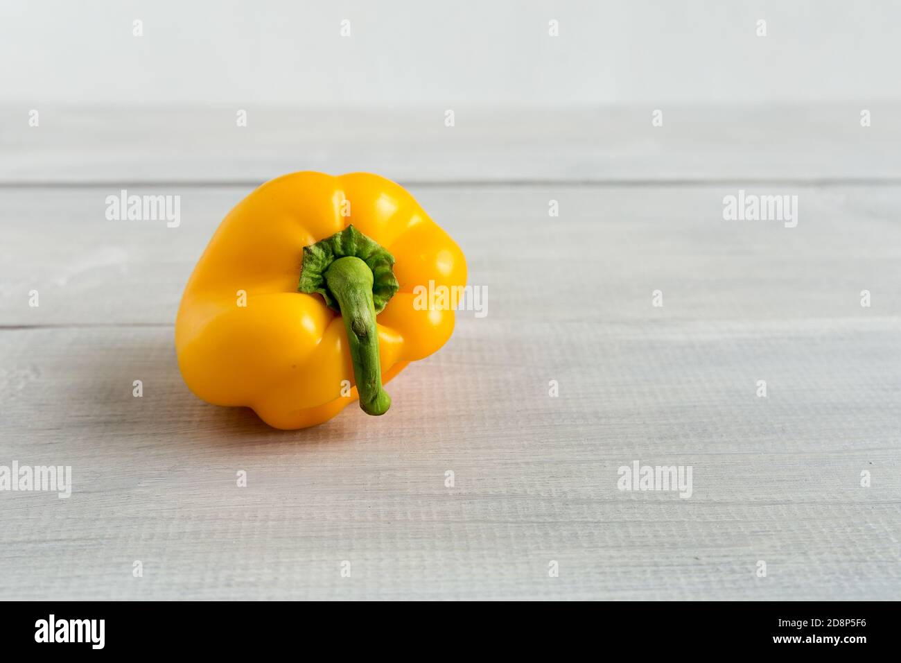 Ugly, deformed, yellow bell pepper isolated on the wooden white background. Strange, funny, imperfect shaped organic vegetable. Food waste problem con Stock Photo