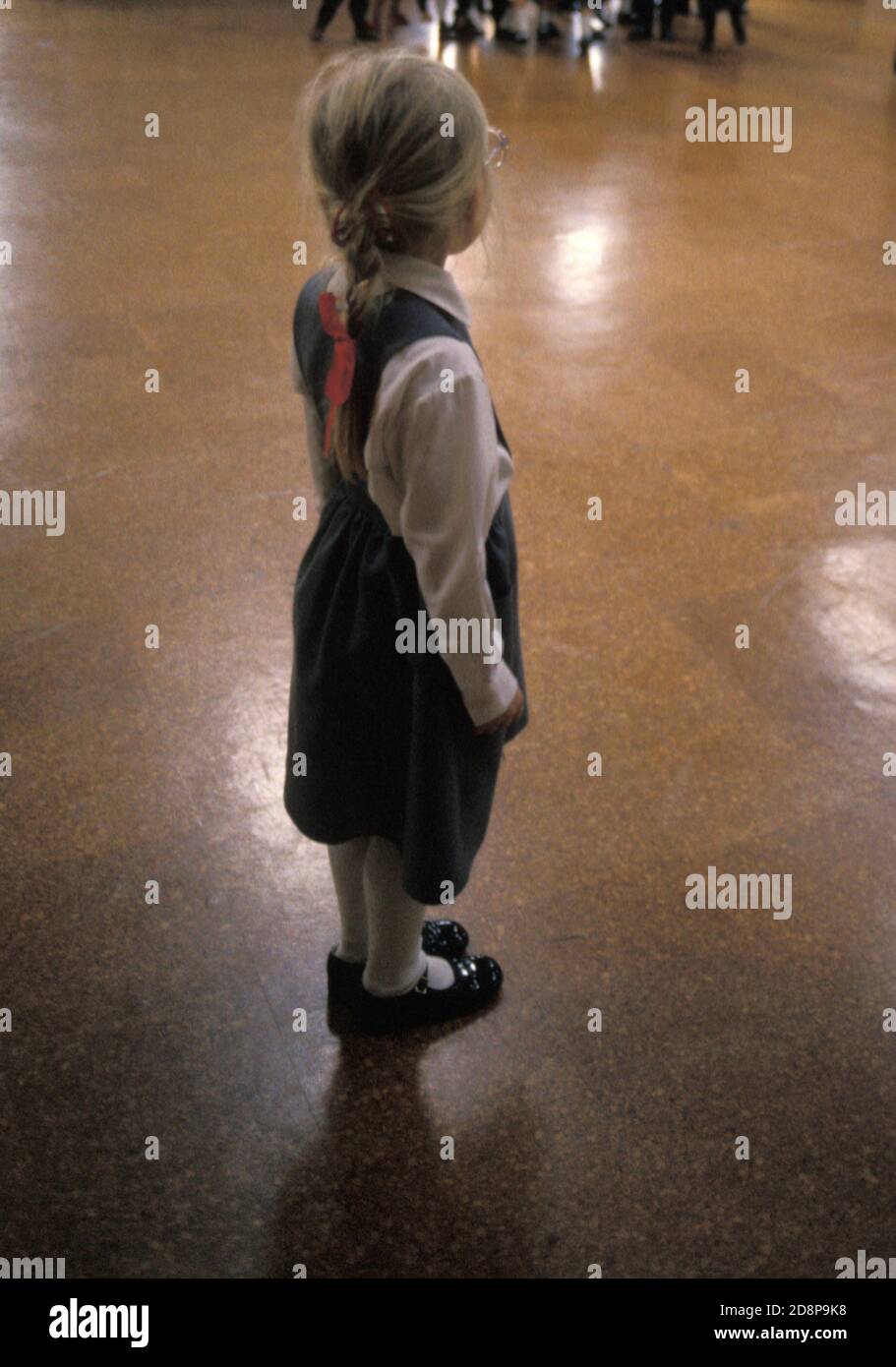 girl in infant school hall standing alone Stock Photo