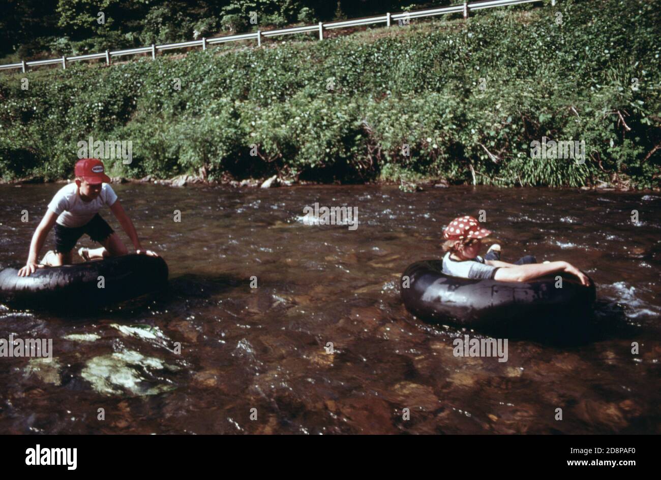 Two youths on truck inner tubes floating down the Chattahoochee River at  Helen. This is one of the favorite summer pastimes for the young residents  of the small mountain community of some
