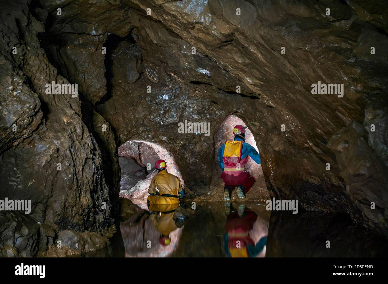 A part-flooded natural cave chamber with two lead miners' tunnels blasted at the far end in Speedwell Cavern in Castleton, Derbyshire. Stock Photo