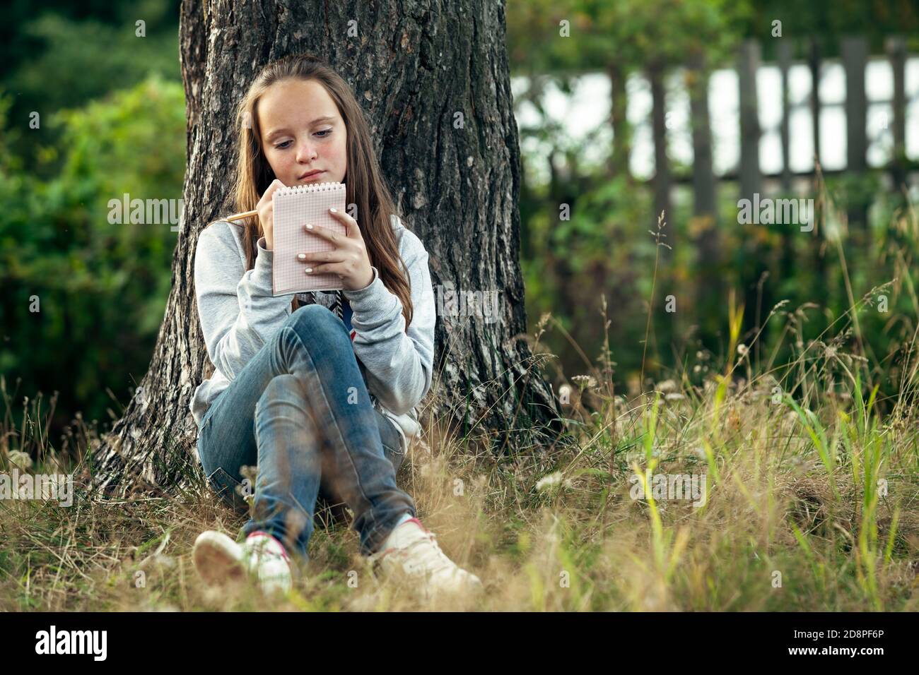 Teen girl writing in a notebook dairy while sitting in the park Stock ...