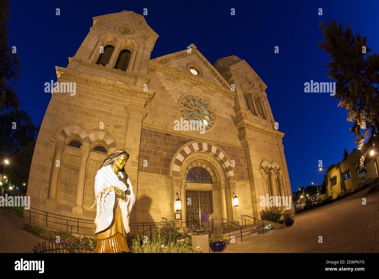 The statue of Saint Kateri Tekakwicha in front of The Cathedral Basilica of St. Francis of Assasi in Santa Fe at twilight with a fish-eye effect and g Stock Photo