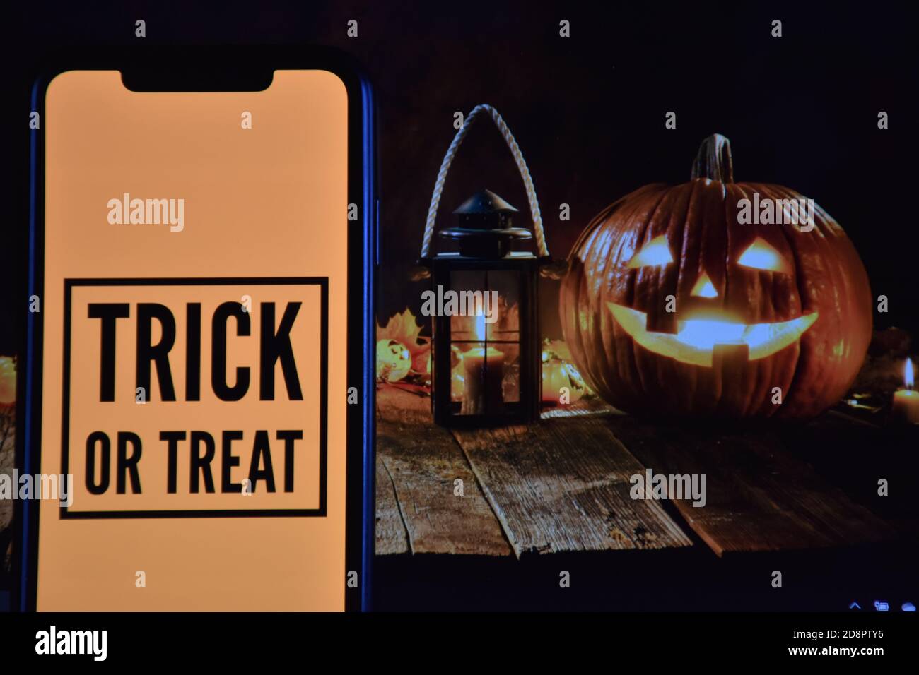 Trick or Treat text on mobile phone with Halloween background Stock