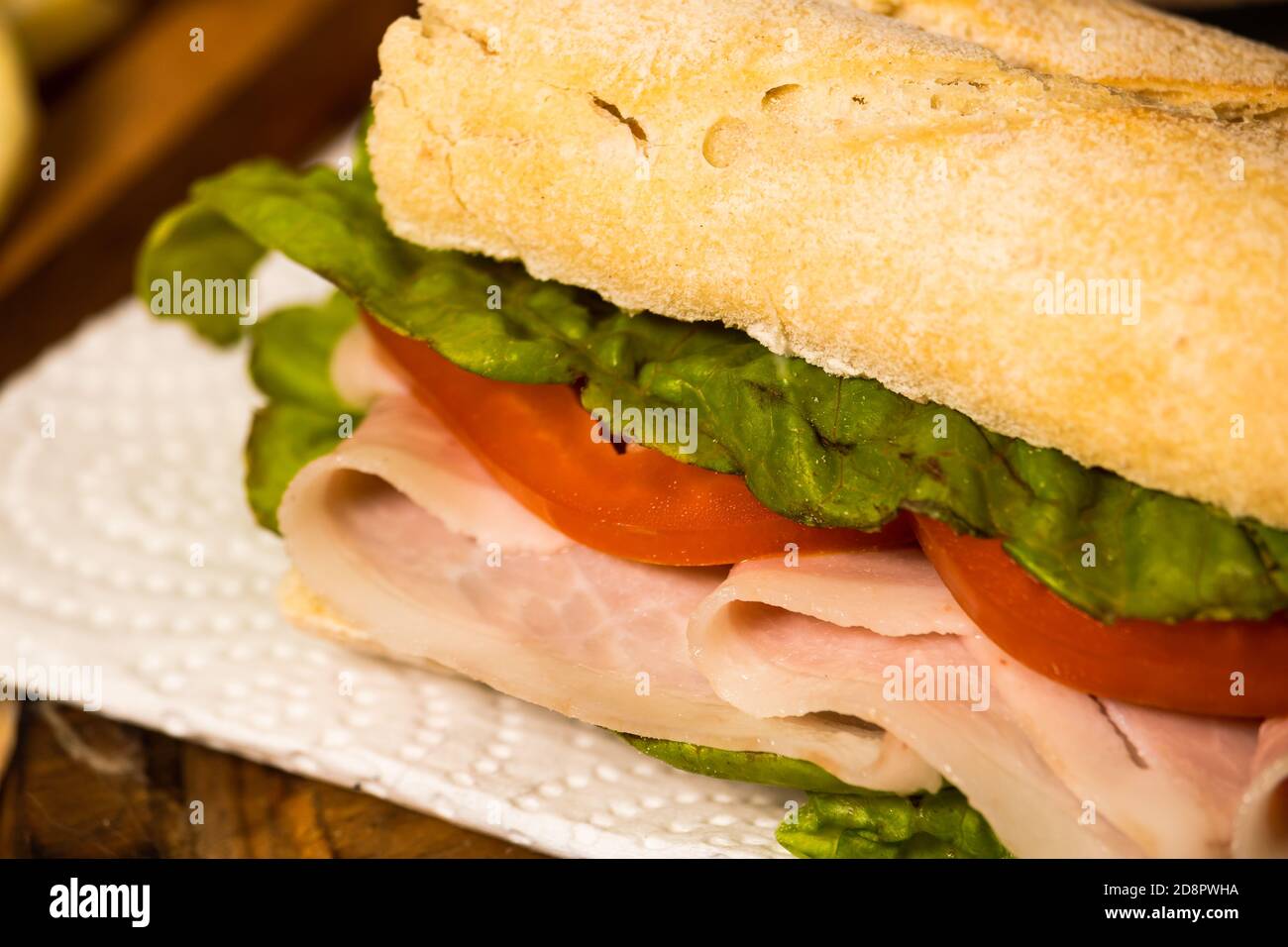 Close up of Ham, tomato and lettuce sandwich on a plate on a 