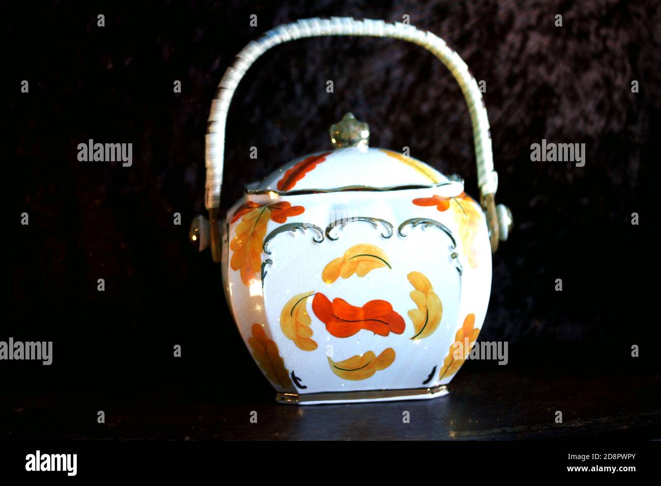 Closeup of a vintage sugar pot with a floral design against a black