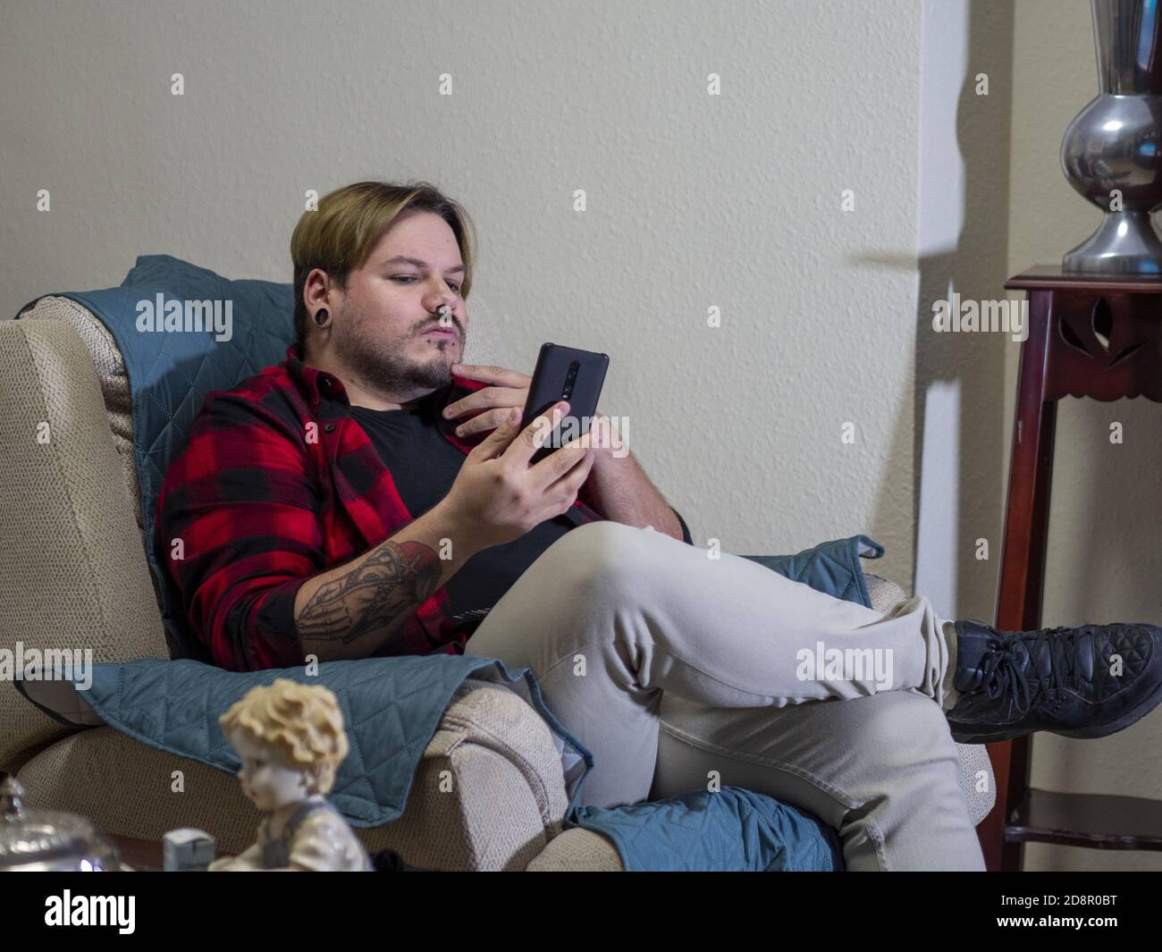 Caucasian man with tattoos looking at his smartphone Stock Photo