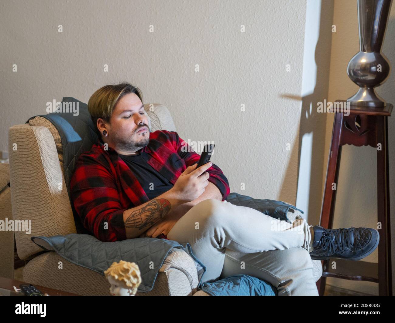 Caucasian man with tattoos looking at his smartphone Stock Photo