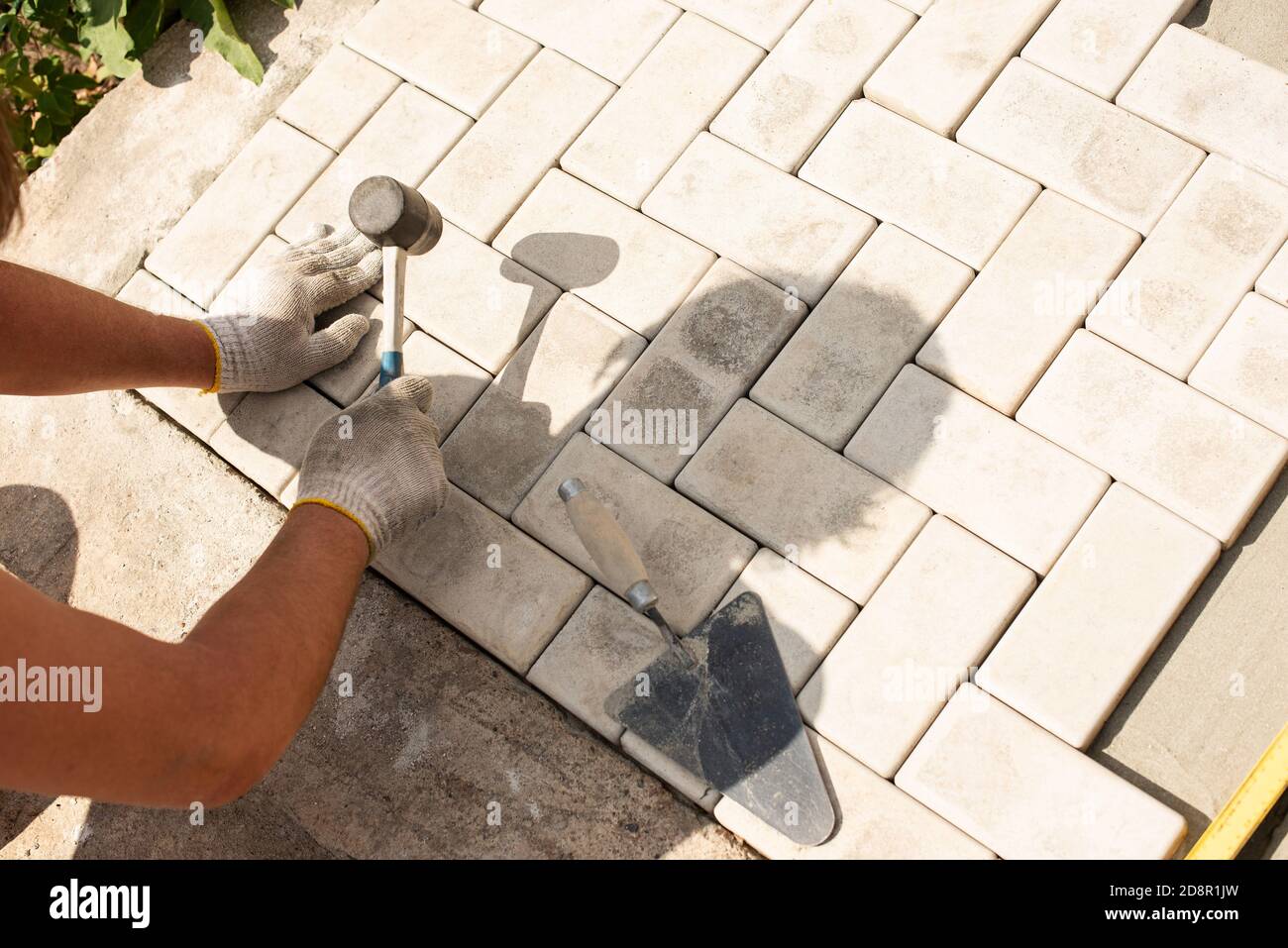 The master lays paving stones in layers. Garden brick pathway paving