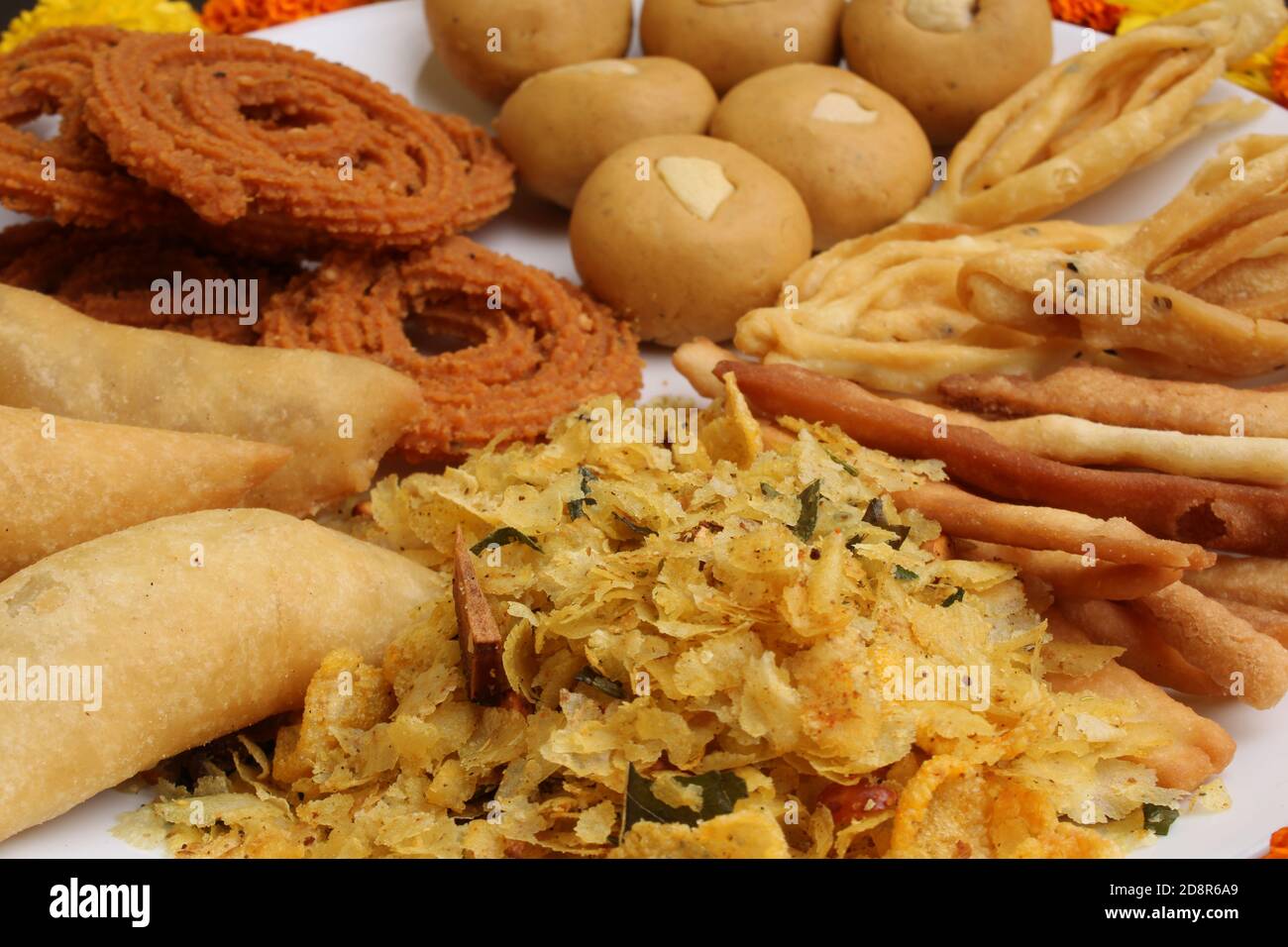 Plate full of indian festival food or diwali food or snacks like laddu, chivda, chakali or murukku and shankar pale, sweet and salty snack food. Stock Photo