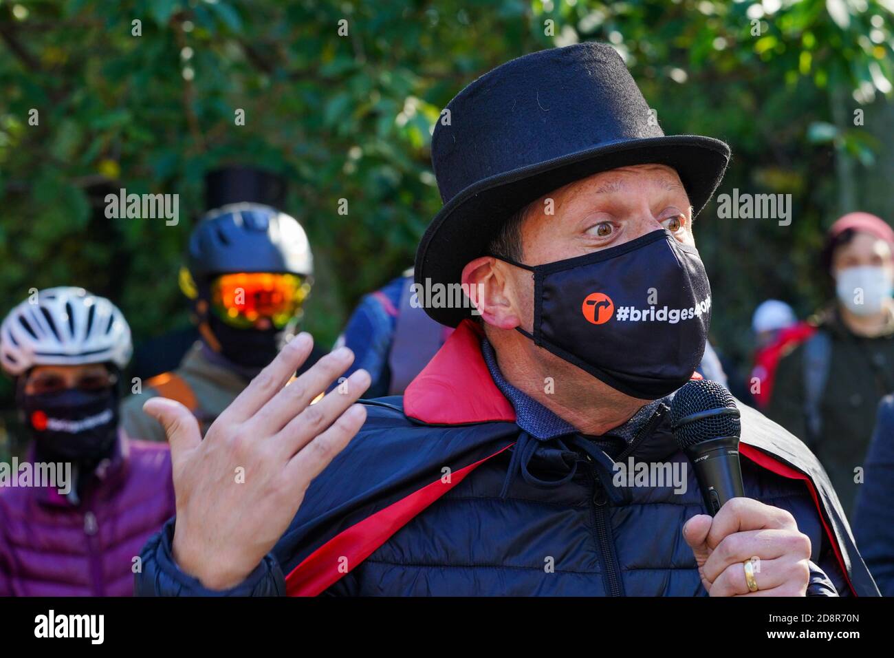 A protester wearing a face mask and costume speaks during a demonstration.Cyclists wearing costumes rode their bikes from the respective boroughs to Gracie Mansion to protest for more space for pedestrians and cyclists on dangerously overcrowded bridges. Stock Photo