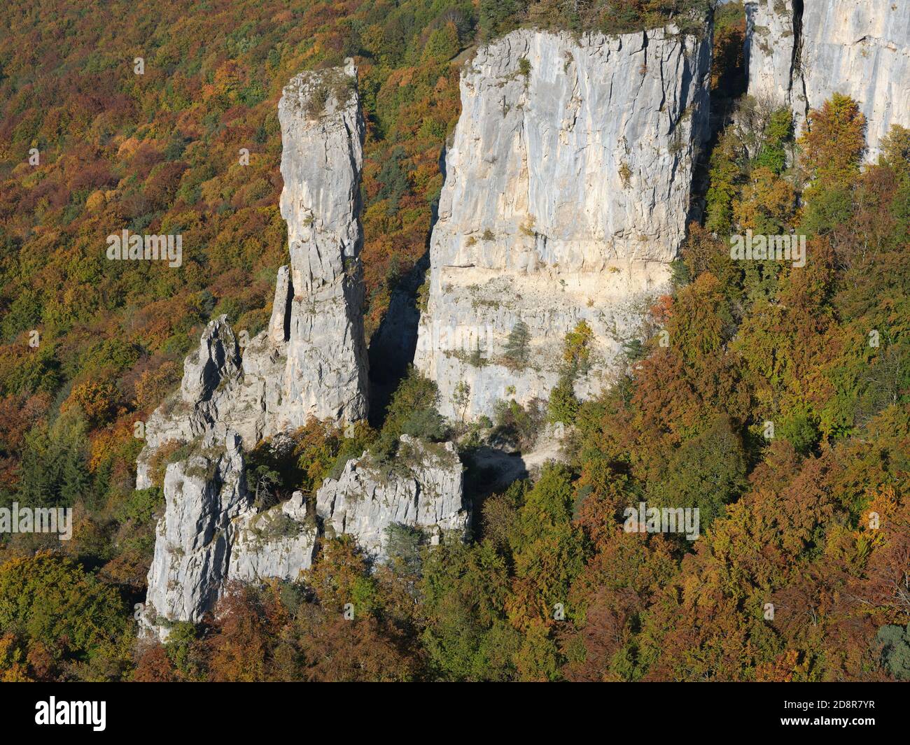 AERIAL VIEW. Lofty limestone pinnacle overlooking an autumnal forest. Tours Saint-Jacques, Allèves, Haute-Savoie, Auvergne-Rhône-Alpes, France. Stock Photo