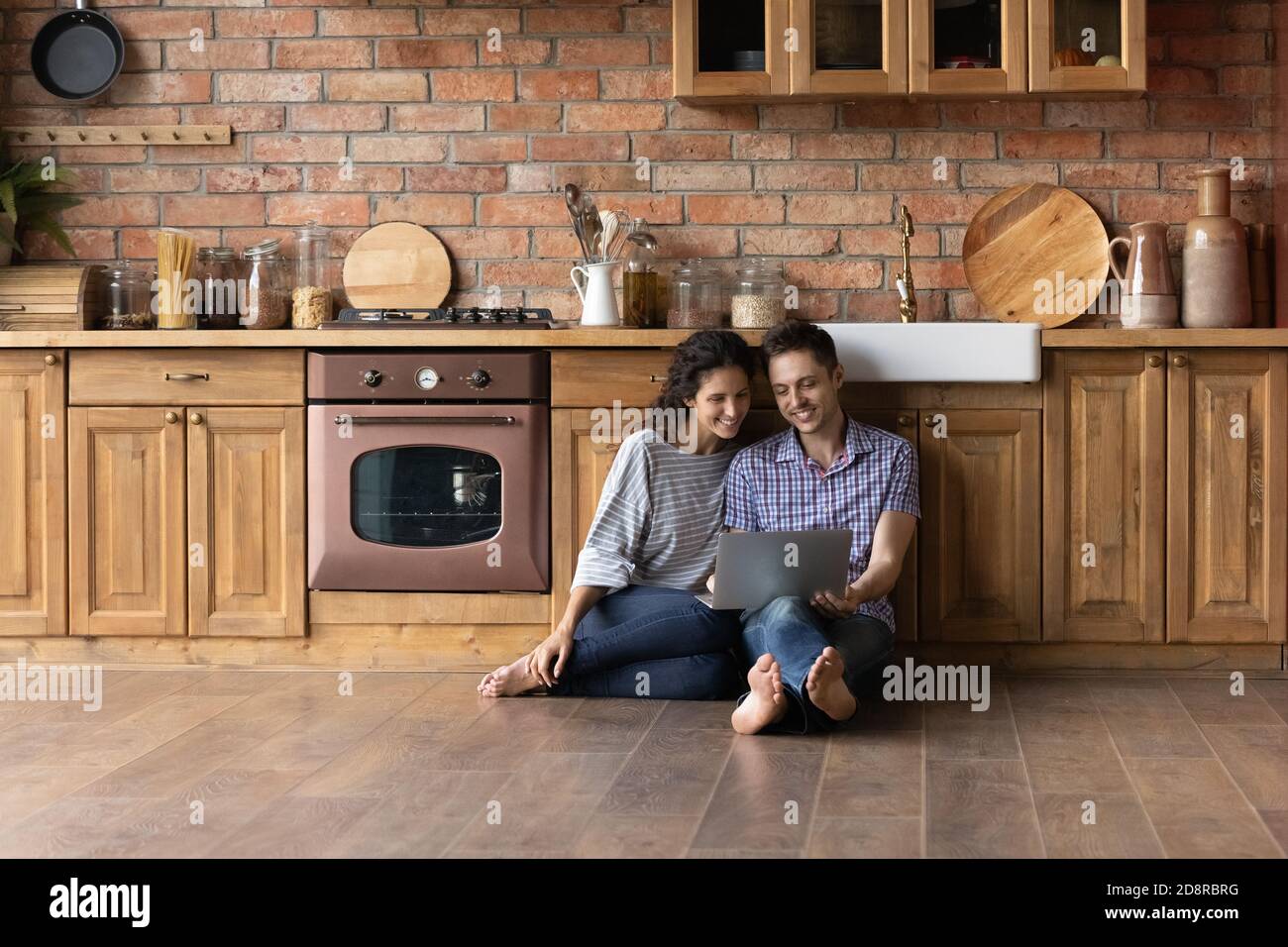 Happy couple relax in cozy kitchen using laptop Stock Photo