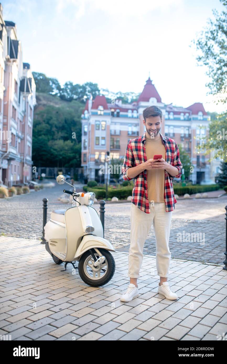 Man having a white scooter texting with his girlfriend Stock Photo Alamy