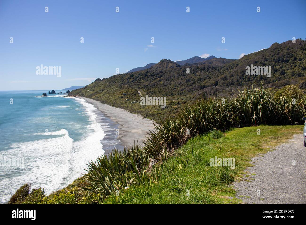 A sea beach in West coast New Zealand surrounded by mountains and green bushes and trees Stock Photo