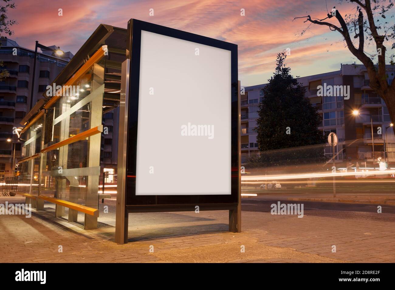 Blank advertisement in a bus stop, with blurred traffic lights Stock Photo