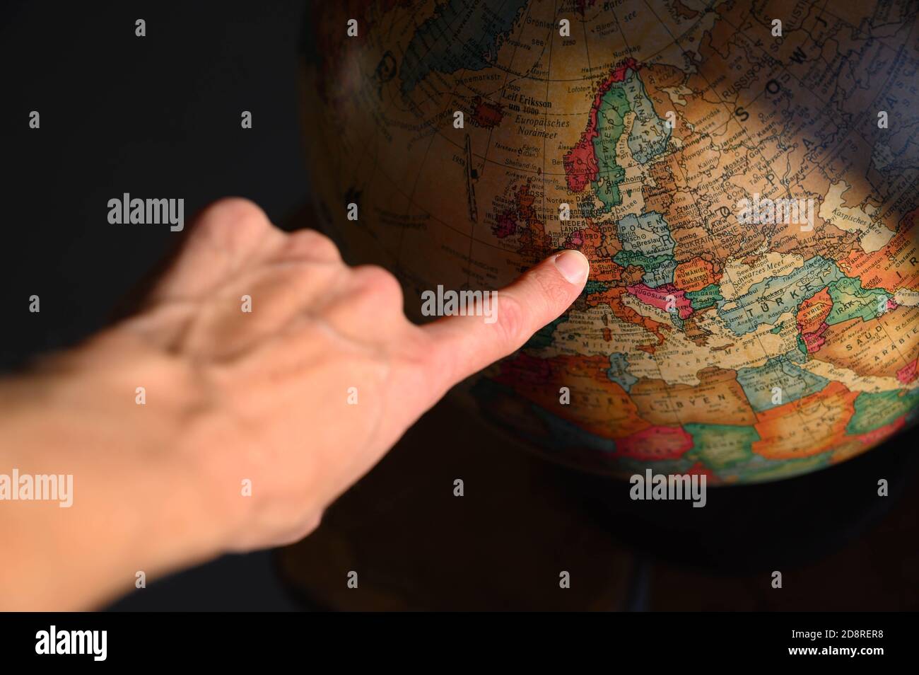 old globe with finger pointing to Europe Stock Photo