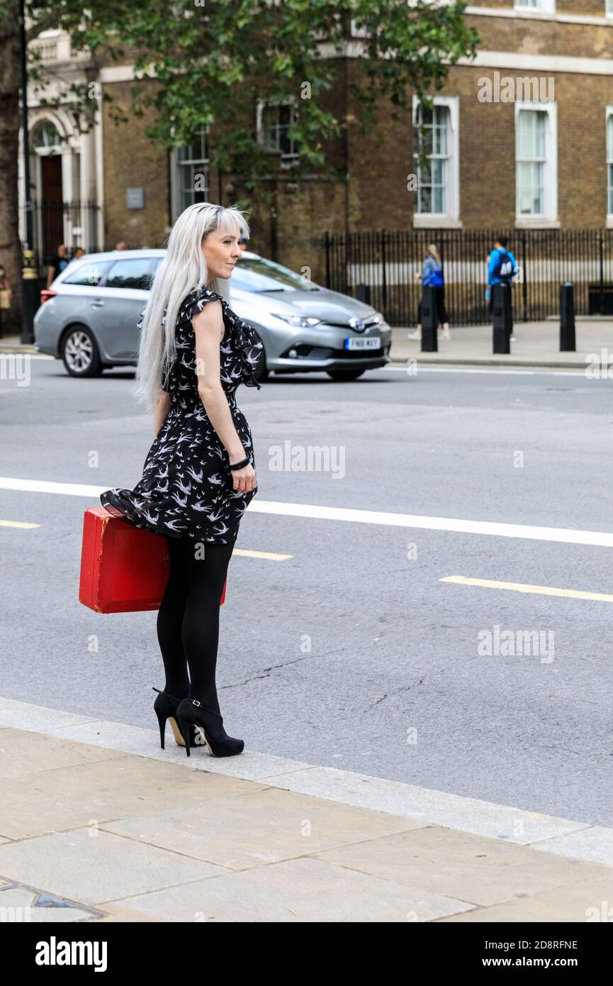 Female ministerial aide holds British government red box, ministerial box (despatch box) outside Cabinet Office, Whitehall, Westminster, London, UK Stock Photo