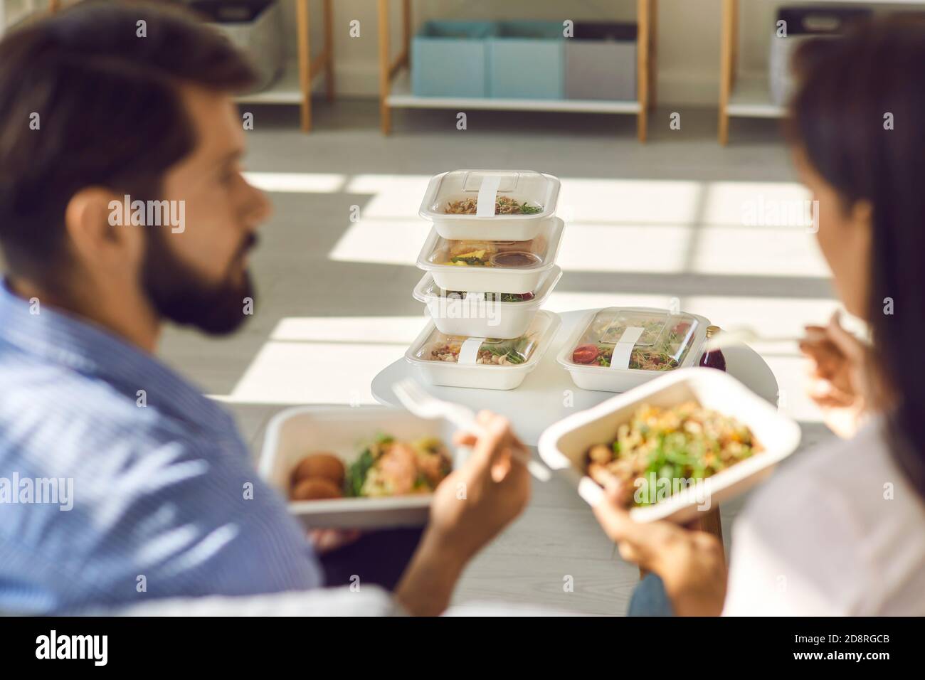 People eating healthy food from containers and discussing set of meals delivered for the whole day Stock Photo