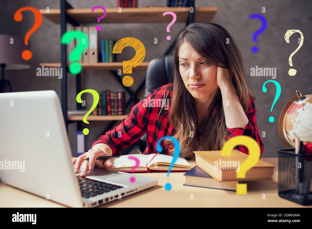 Woman teleworker works at home with a laptop with a lot of questions. She is in smart working due to covid-19 pandemic Stock Photo