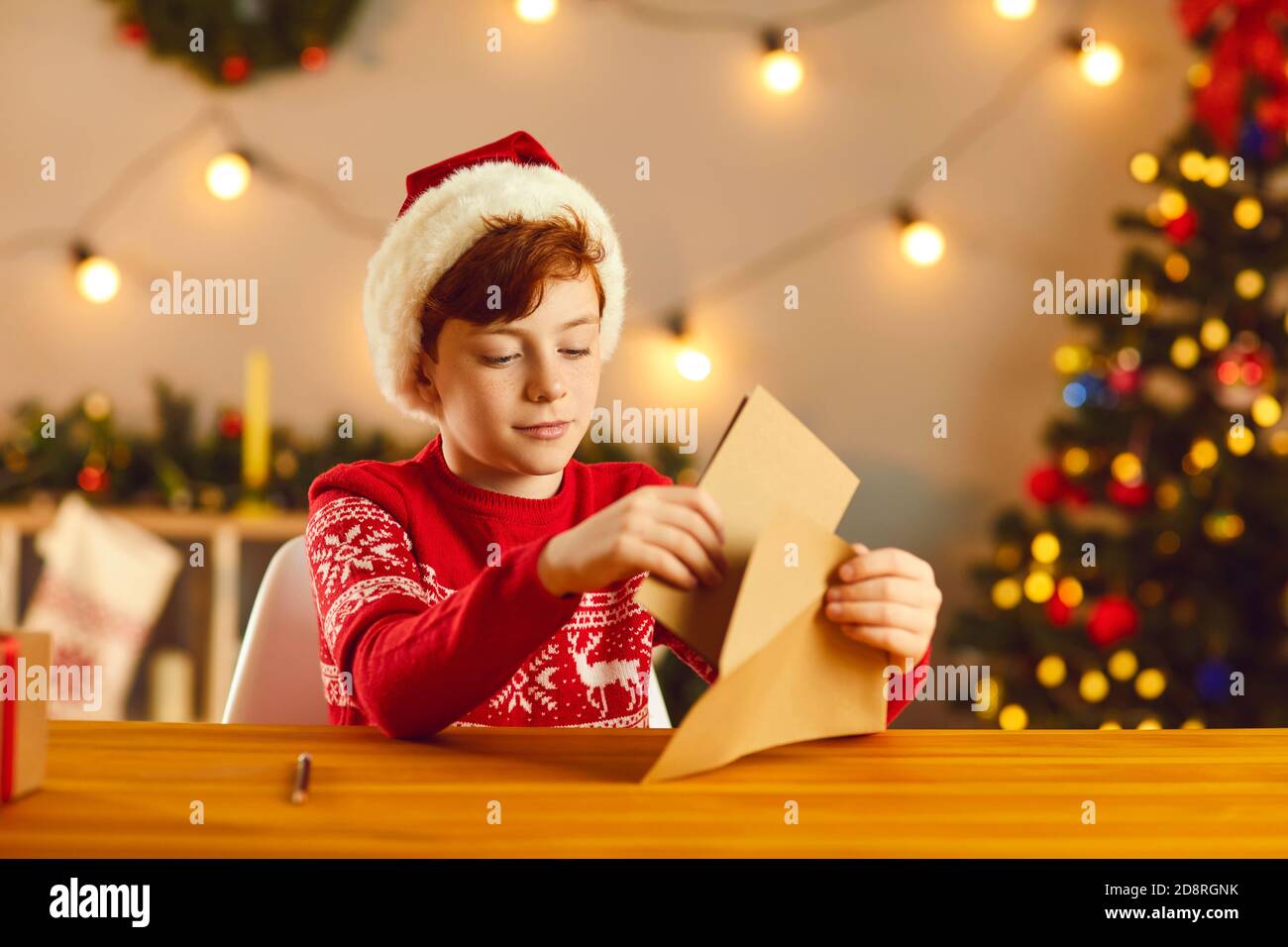 Little boy putting his letter and wish list in an envelope before sending them to Santa Claus Stock Photo