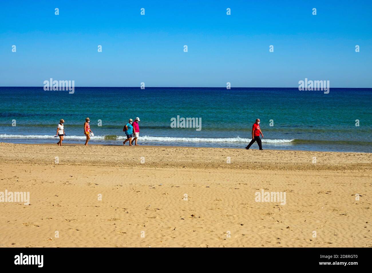 People walking the sandy beaches, wearing facemasks, at La Mata, Torrevieja,Costa Blanca, Spain, winter, winter sun, destination Stock Photo