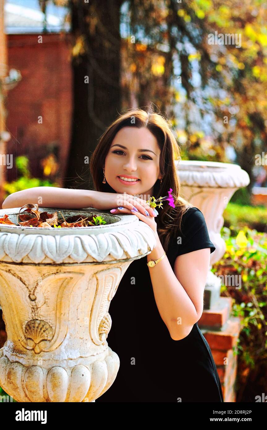portrait of young happy woman in black dress in autumn city with a basket of flowers Stock Photo