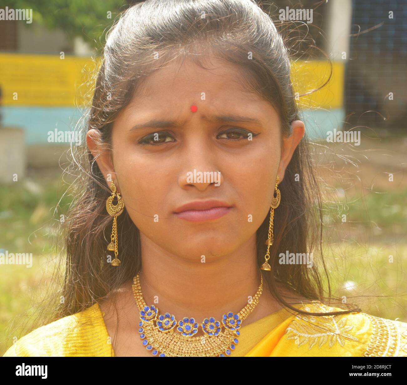 Close up of  Indian Bengali teenage girl wearing traditional Indian saree with golden jewellery erring necklace and bindi on forehead, selective focus Stock Photo