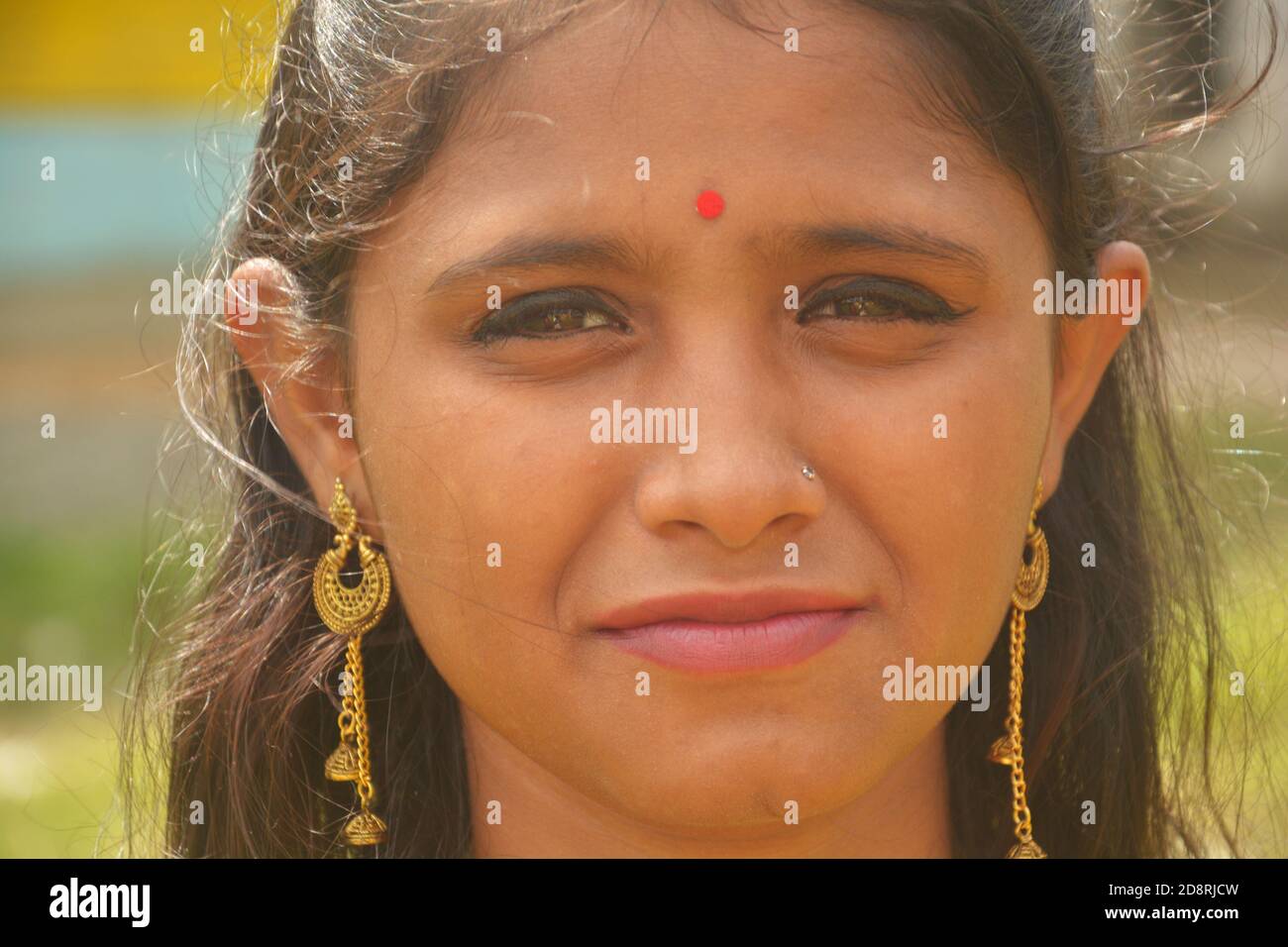 Close up of  Indian Bengali teenage girl wearing traditional Indian saree with golden jewellery erring necklace and bindi on forehead, selective focus Stock Photo