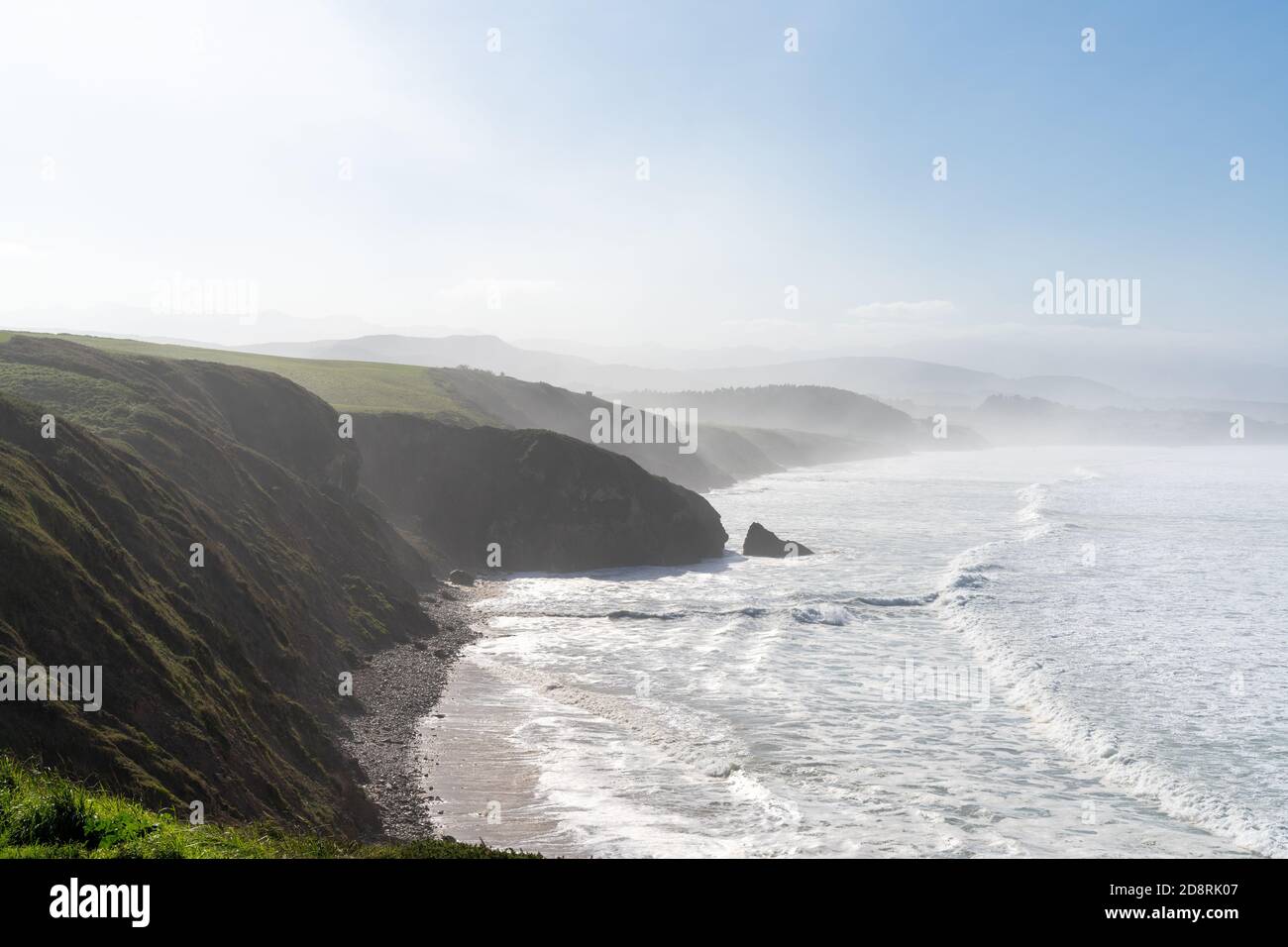 Tall green grassy cliffs drop down to the ocean coast in northern Spain Stock Photo