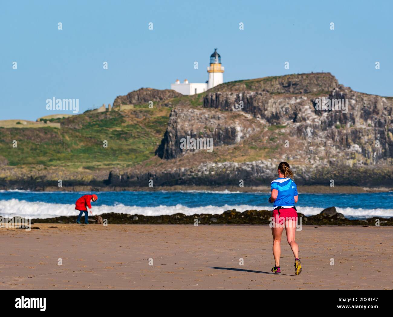 Female runner, Yellowcraig  beach with Fidra Island & lighthouse, East Lothian, Scotland, UK Stock Photo