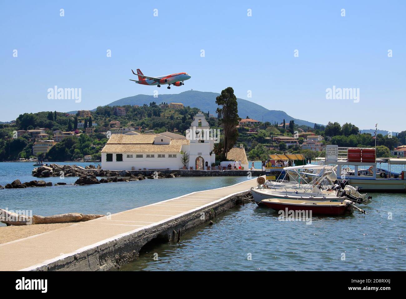 Airplane landing over church on Corfu Stock Photo