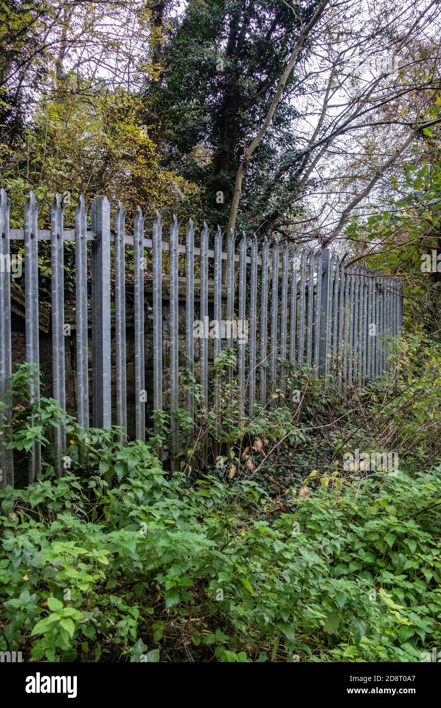 Galvanised steel palisade spiked security fencing on railway banks Stock Photo