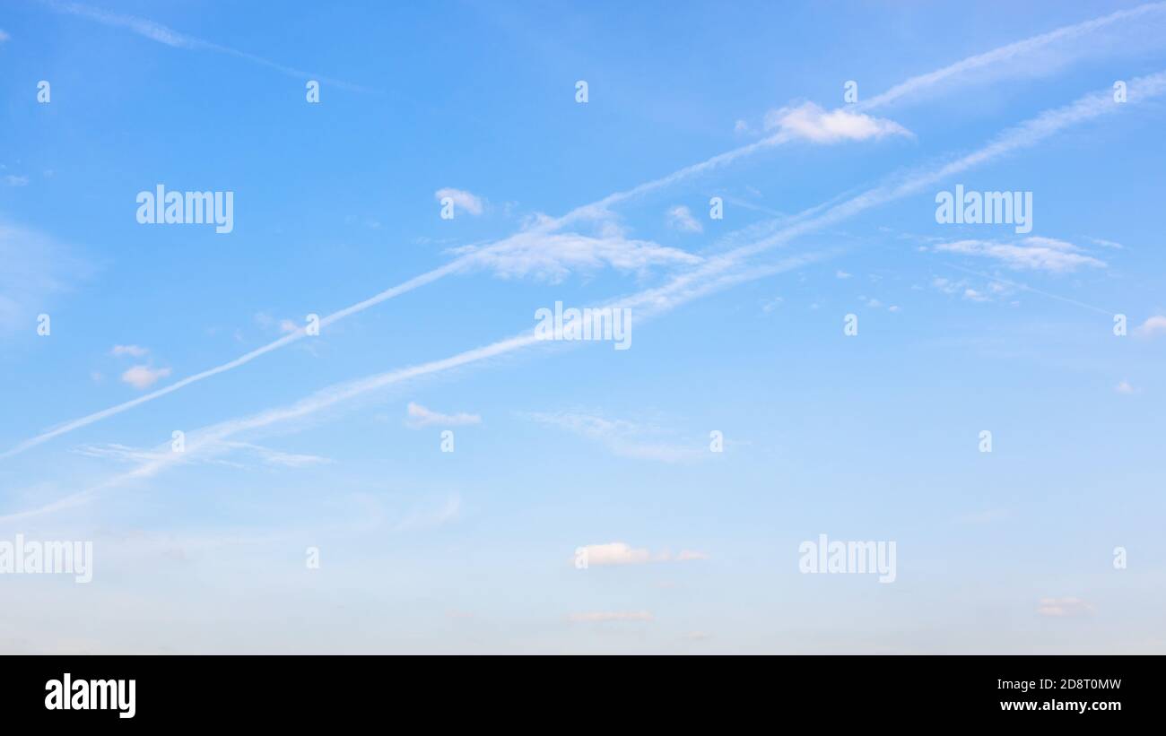 low contrail and little cumuli clouds in blue sky on autumn day Stock Photo