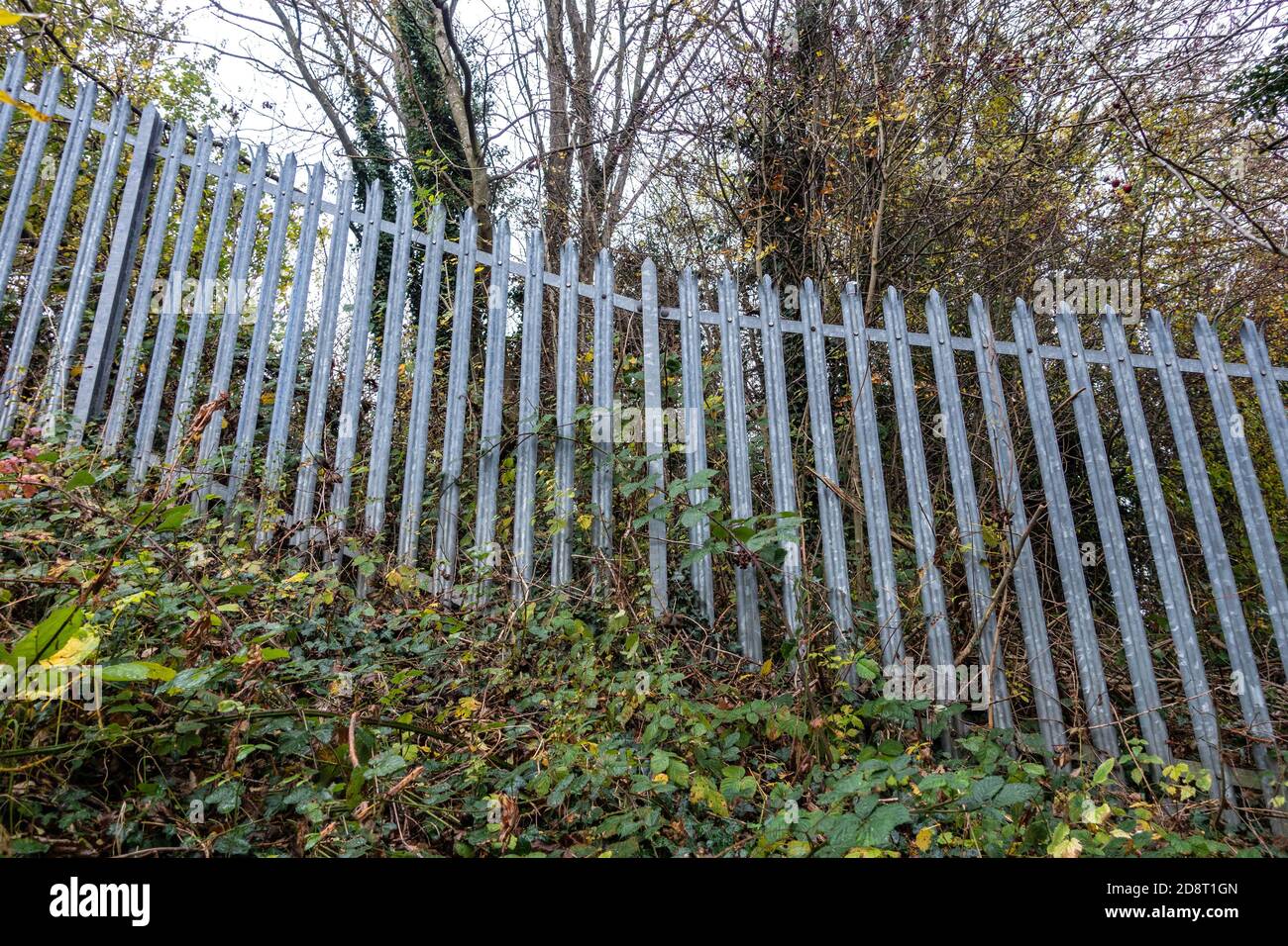 Galvanised steel palisade spiked security fencing on railway banks Stock Photo