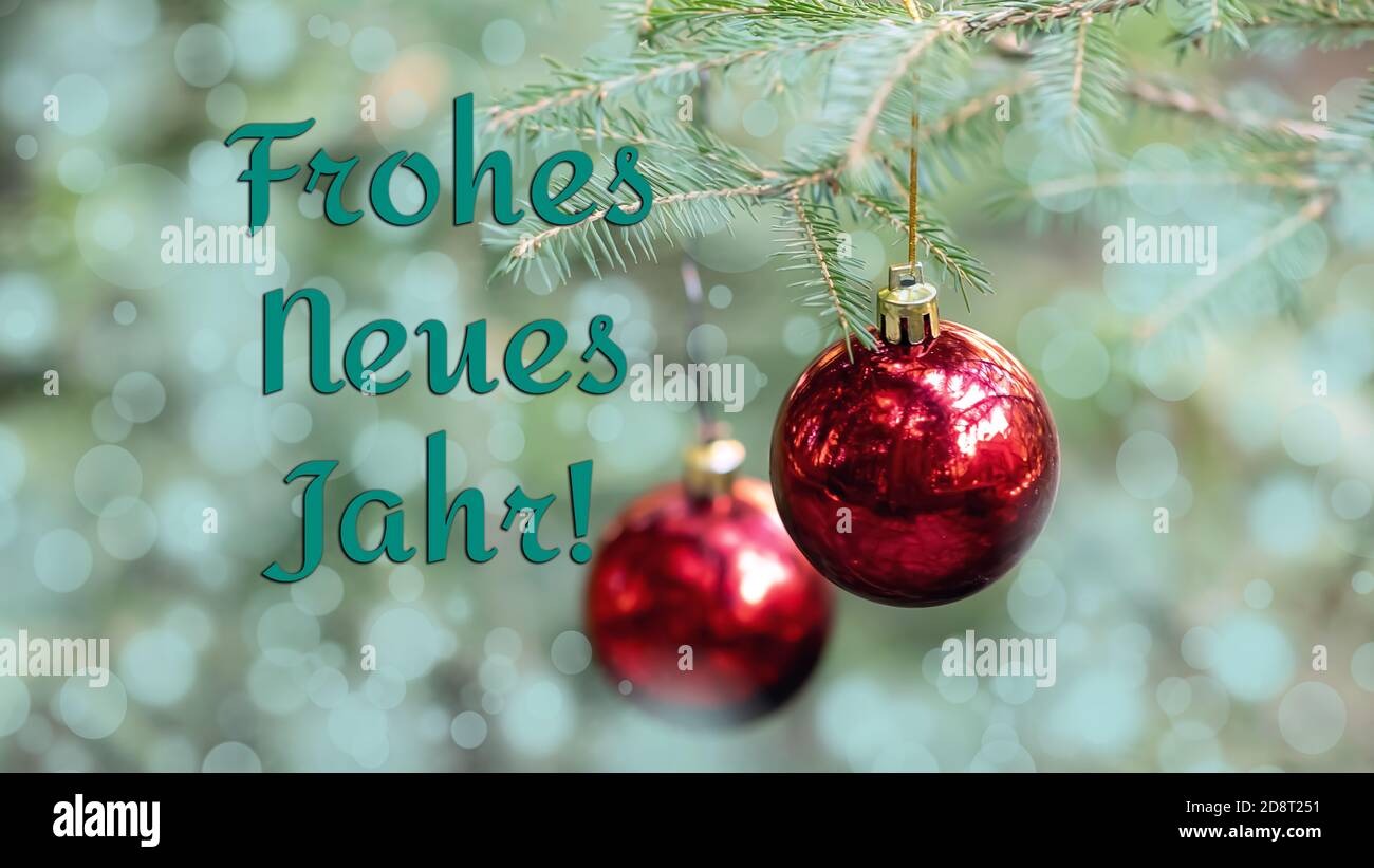 Happy New Year greetings in German. The blurred background of the Christmas tree is decorated red balls. Bokeh. Christmas banner Stock Photo