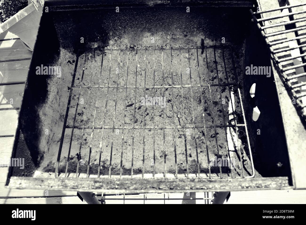 View of the open charcoal grill after use with ashes at the bottom of