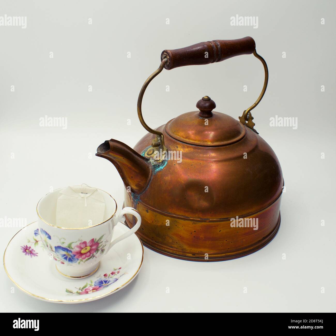 Close up on old copper tea kettle next to flower themed tea cup and saucer Stock Photo Alamy