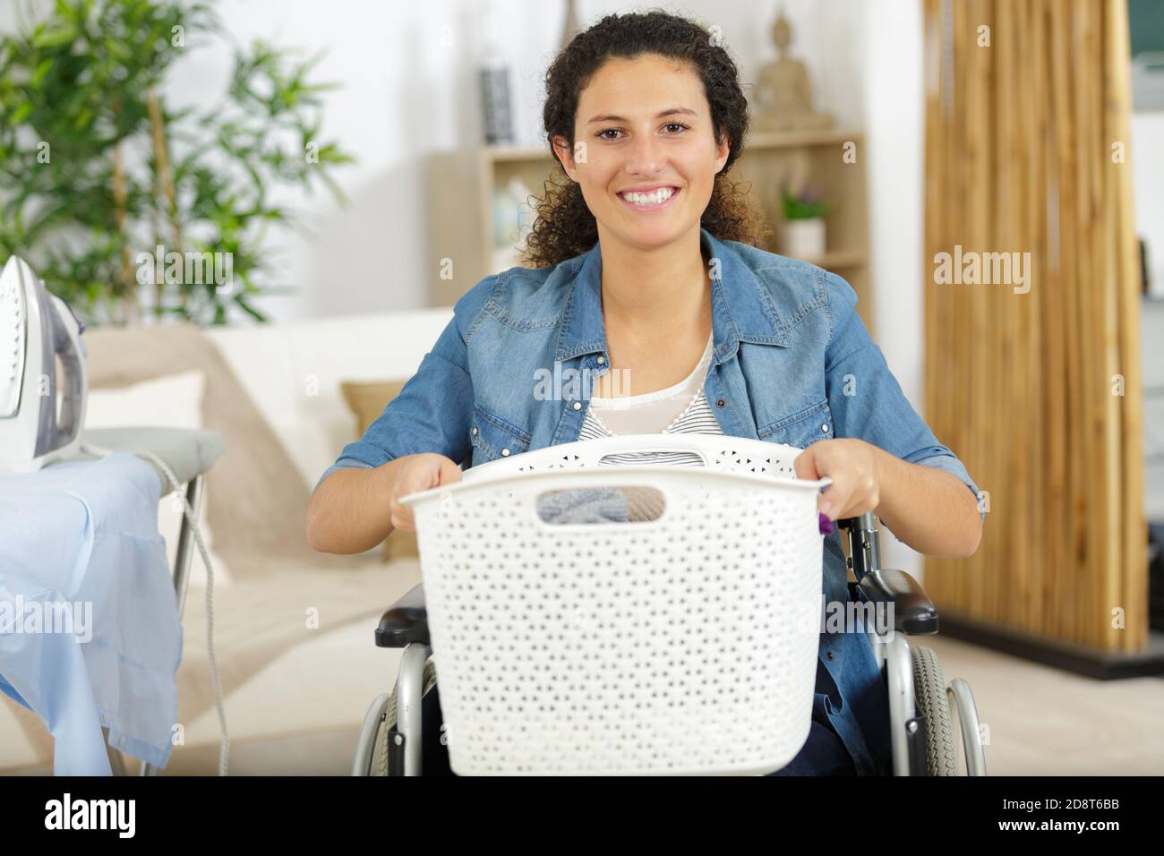 disabled woman in a wheelchair carrying a laundry basket Stock Photo