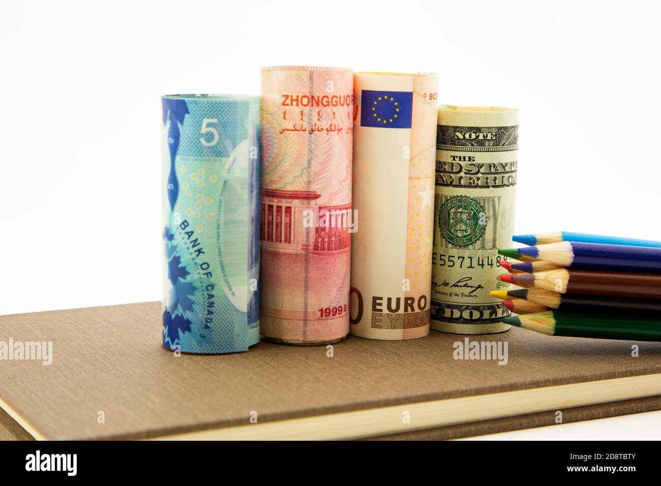 Conceptual multinational business image seen in ledger, colored pencils, and money from Canada, China, European Union, and United States Stock Photo