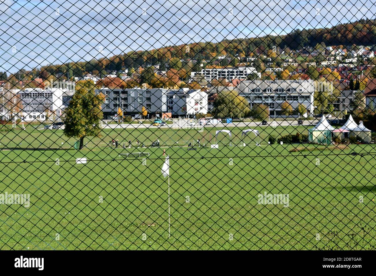 Golf club in Urdorf on a sunny autumn Saturday afternoon from behind a fence with village center in the background. Stock Photo