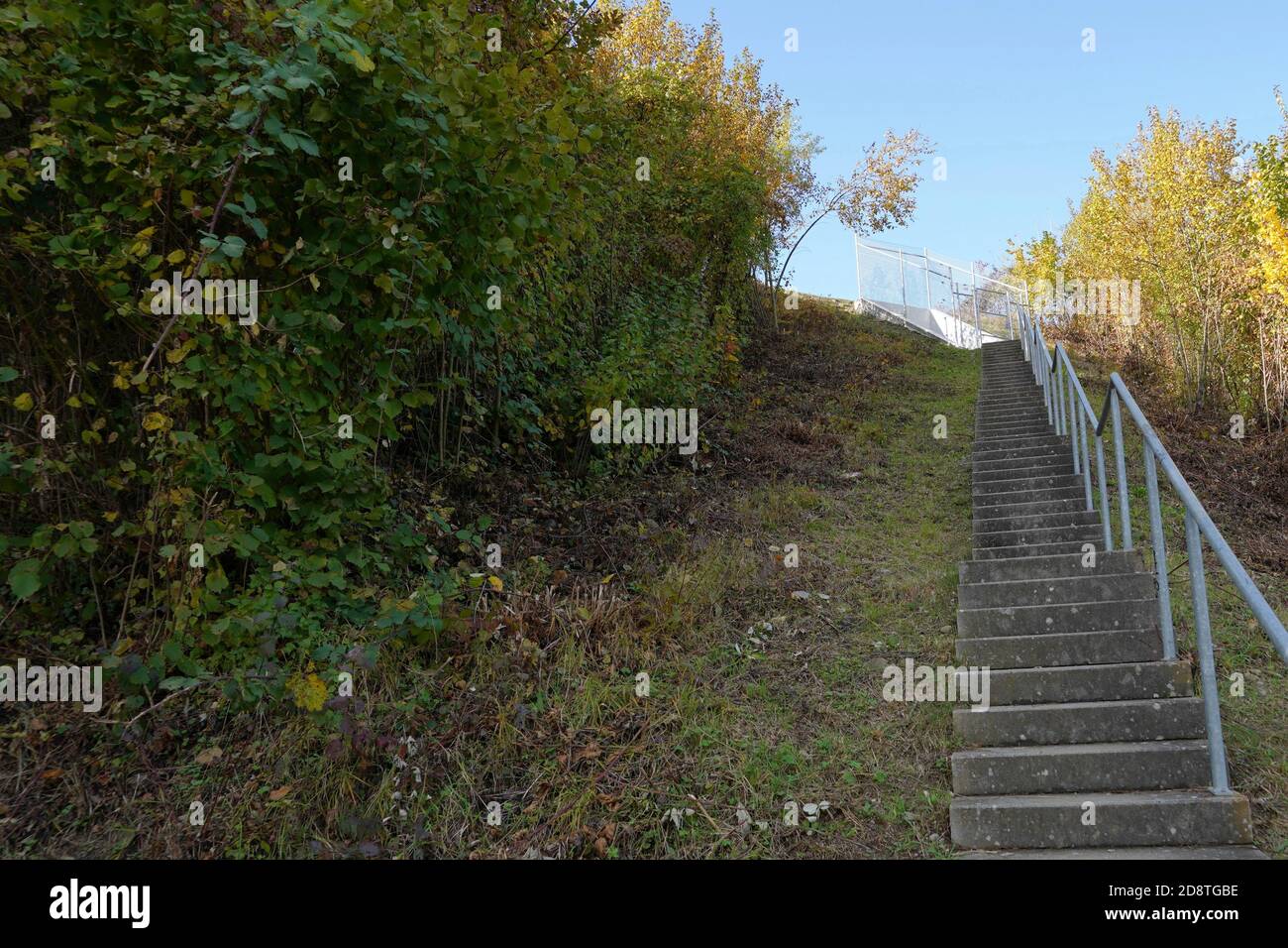 Emergency staircase from an emergency exit on  a highway. The staircase is made of cement and has a metal railings on one side, it is bordered on both Stock Photo