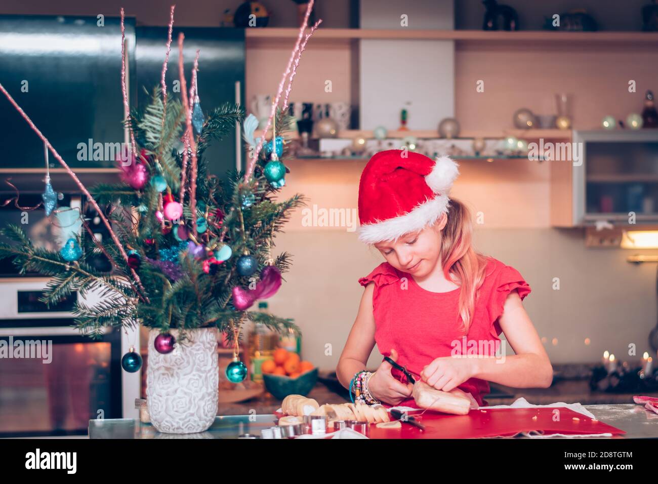 lovely blond girl in christmas hat preparing sweets in christmas atmosphere in the home kitchen Stock Photo
