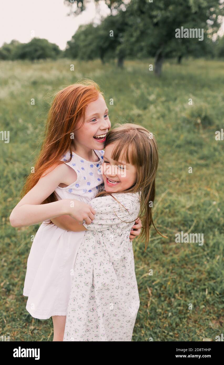 two little girls sisters play and have fun on the grass holding hands ...