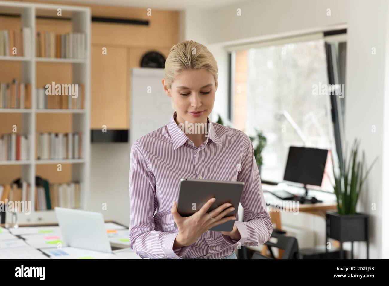 Pleasant smiling young businesswoman using computer tablet. Stock Photo