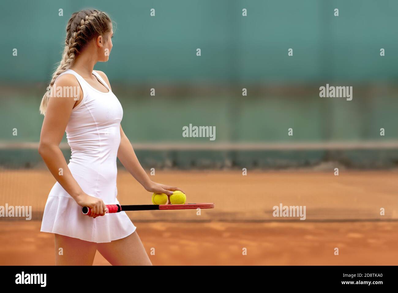 Tennis player in white sportswear preparing to serve tennis ball