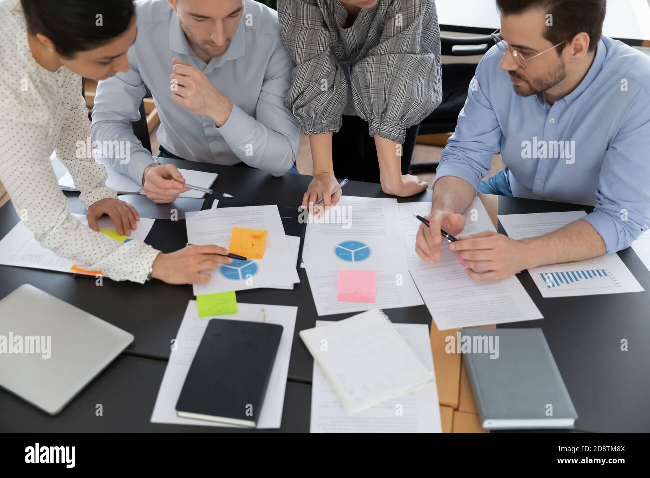 Top view focused young serious multiracial teammates doing paperwork. Stock Photo