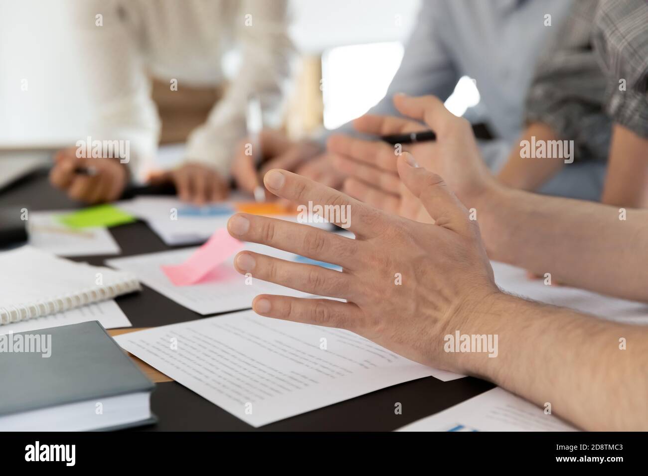 Close up young male employee gesturing, sharing project ideas. Stock Photo